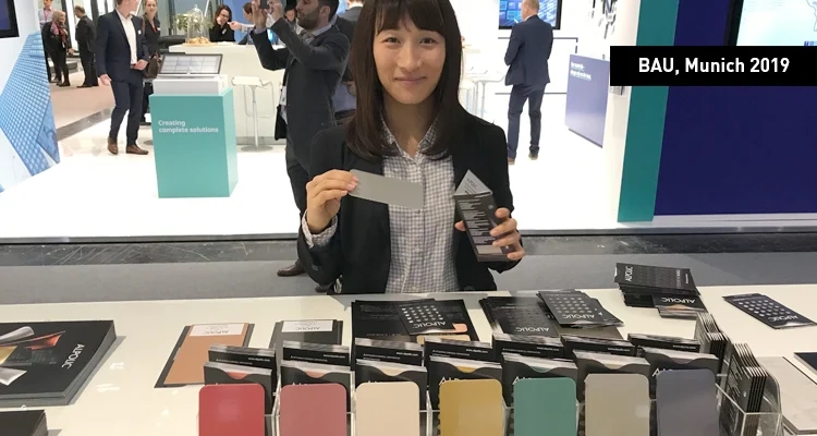ALPOLIC™ : Stand d'exposition BAU 2019 Présentation des échantillons de couleurs sur le stand d'exposition avec une femme en arrière-plan tenant les échantillons à la main.